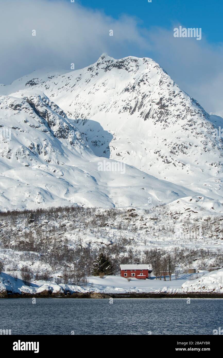 Vue sur les montagnes enneigées et les maisons de l'île d'Austvag près du célèbre Trollfjord dans les îles Lofoten, comté de Nordland, Norvège. Banque D'Images