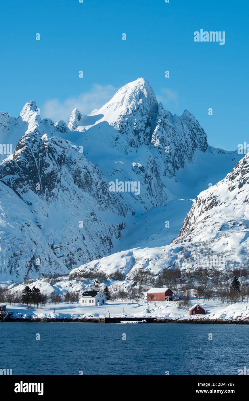 Vue sur les montagnes enneigées et les maisons de l'île d'Austvag près du célèbre Trollfjord dans les îles Lofoten, comté de Nordland, Norvège. Banque D'Images