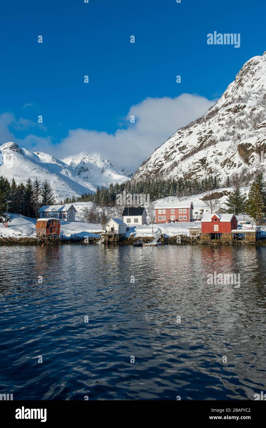 Vue sur les montagnes enneigées et les maisons de l'île d'Austvag près du célèbre Trollfjord dans les îles Lofoten, comté de Nordland, Norvège. Banque D'Images