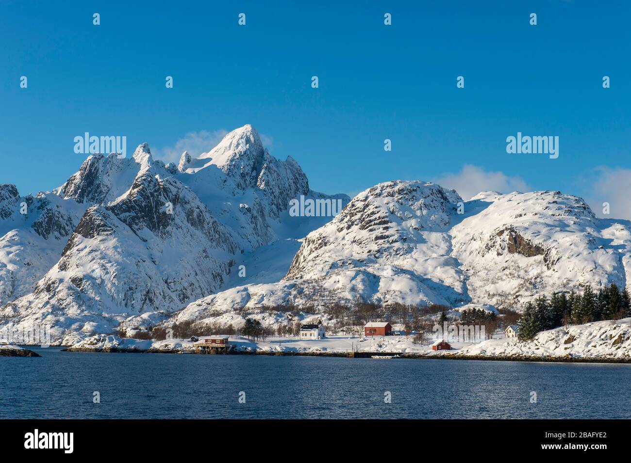 Vue sur les montagnes enneigées et les maisons de l'île d'Austvag près du célèbre Trollfjord dans les îles Lofoten, comté de Nordland, Norvège. Banque D'Images