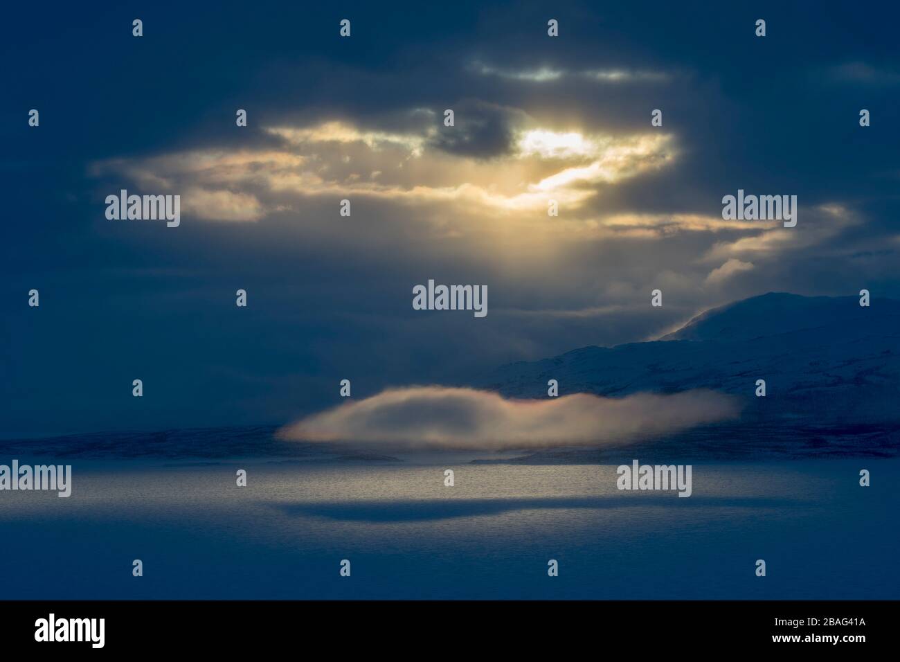 Vue depuis la zone de l'hôtel Fjallet avec une lumière spectaculaire et des nuages sur le lac Tornetrask gelé et enneigé en Laponie suédoise, dans le nord de la Suède. Banque D'Images