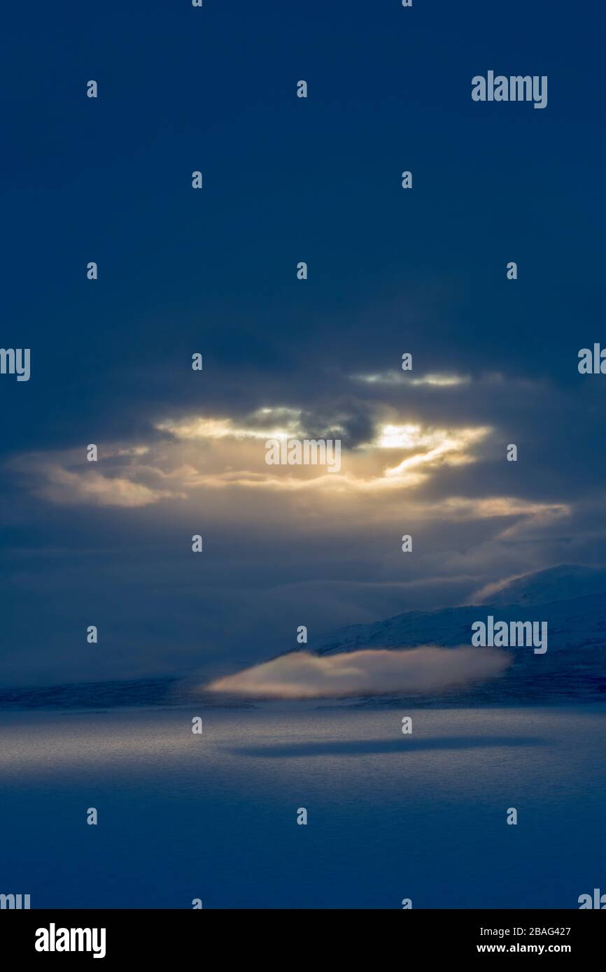 Vue depuis la zone de l'hôtel Fjallet avec une lumière spectaculaire et des nuages sur le lac Tornetrask gelé et enneigé en Laponie suédoise, dans le nord de la Suède. Banque D'Images