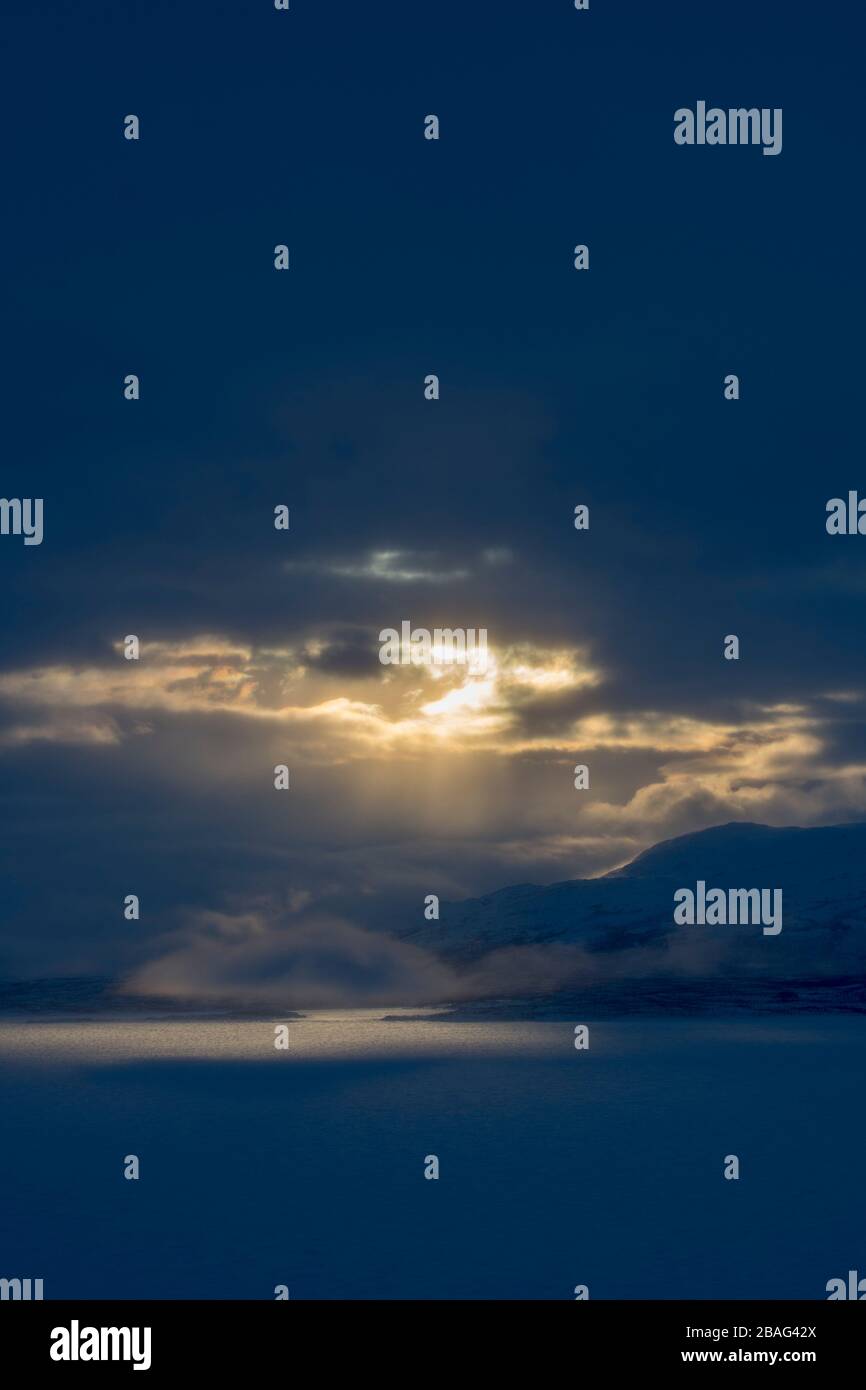 Vue depuis la zone de l'hôtel Fjallet avec une lumière spectaculaire et des nuages sur le lac Tornetrask gelé et enneigé en Laponie suédoise, dans le nord de la Suède. Banque D'Images