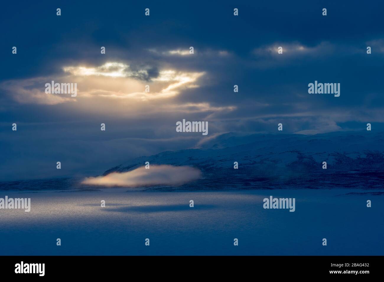Vue depuis la zone de l'hôtel Fjallet avec une lumière spectaculaire et des nuages sur le lac Tornetrask gelé et enneigé en Laponie suédoise, dans le nord de la Suède. Banque D'Images
