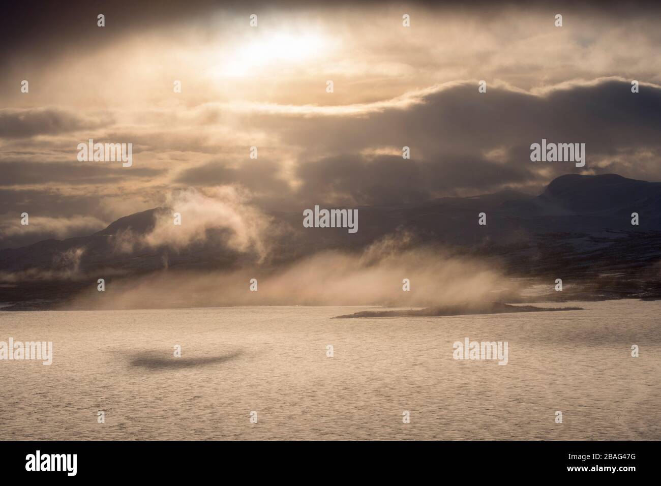 Vue depuis la zone de l'hôtel Fjallet avec une lumière spectaculaire et des nuages sur le lac Tornetrask gelé et enneigé en Laponie suédoise, dans le nord de la Suède. Banque D'Images