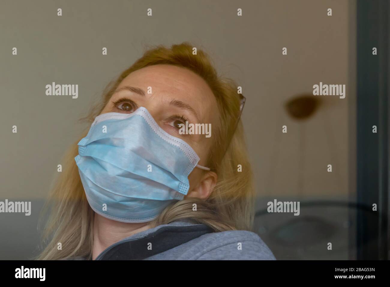 Femme blonde italienne avec masque de protection forcé de rester fermé à la maison pour la quarantaine suite à la propagation du coronavirus Covid-19 Banque D'Images