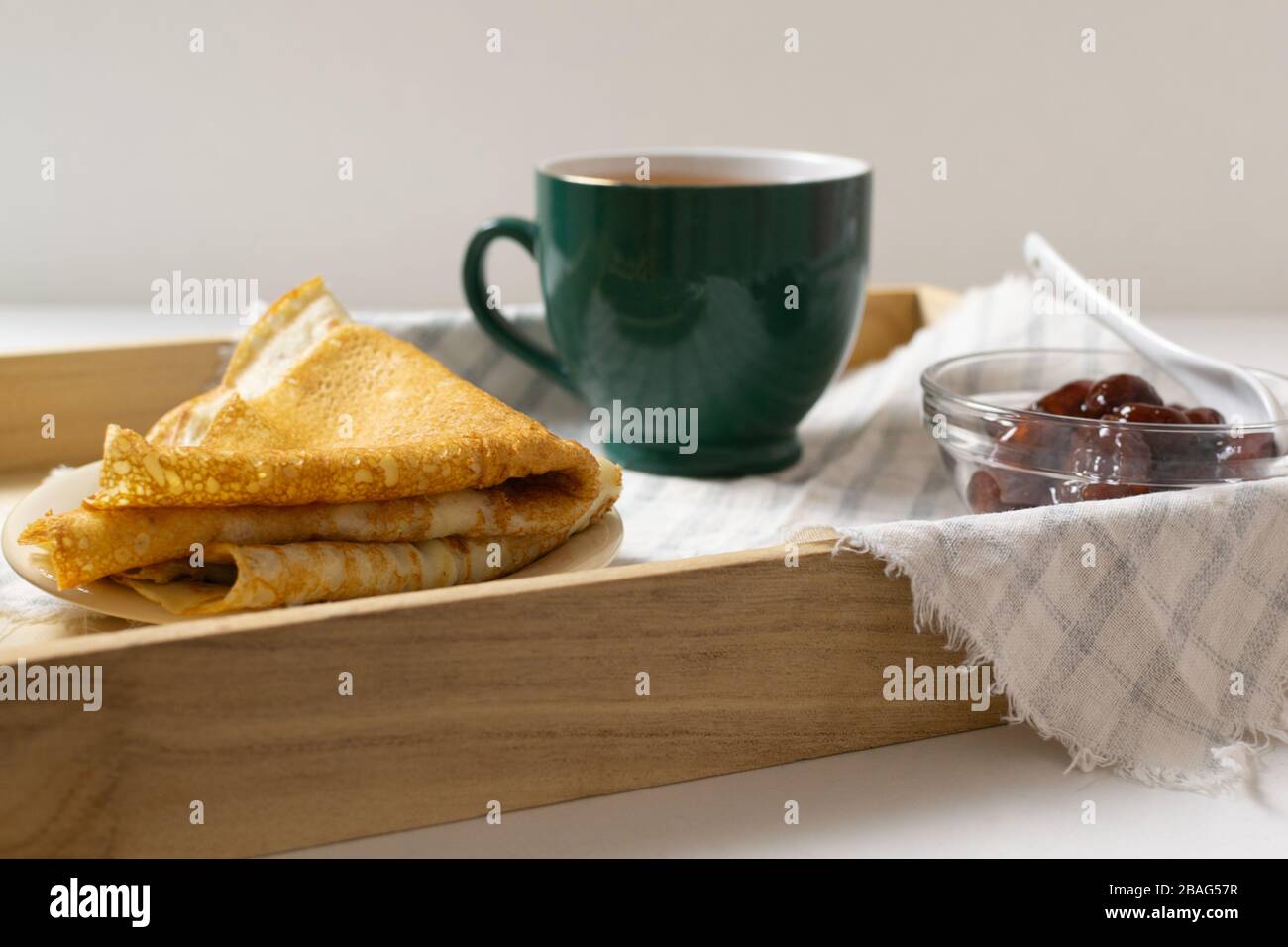 Crêpes (lini russe) avec confiture de fraises et thé sur un plateau. Petit déjeuner. Сlose haut. Banque D'Images