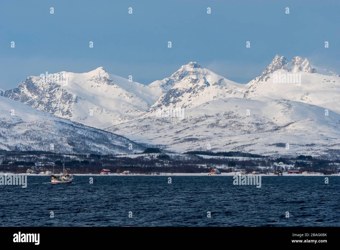 Vue sur un bateau de pêche et sur le paysage enneigé du fjord de Tromso près de la ville de Tromso, dans le comté de Troms og Finnmark, en Norvège. Banque D'Images