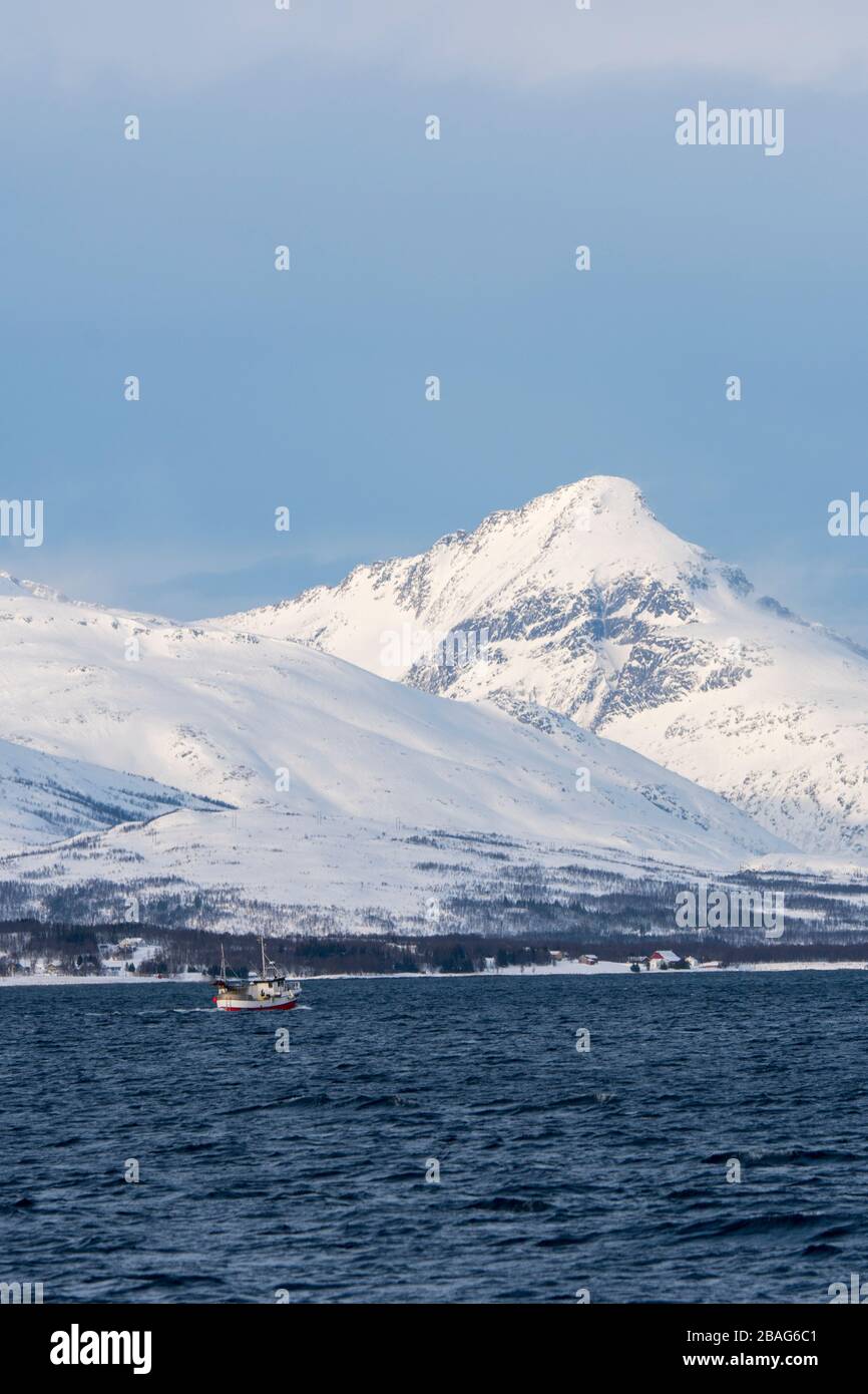 Vue sur un bateau de pêche et sur le paysage enneigé du fjord de Tromso près de la ville de Tromso, dans le comté de Troms og Finnmark, en Norvège. Banque D'Images