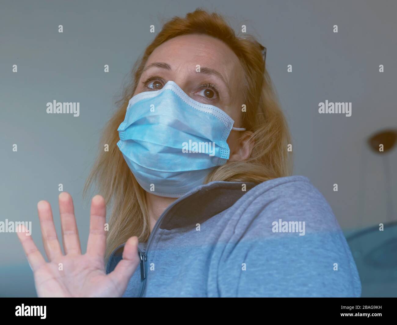 Femme blonde italienne avec masque de protection forcé de rester fermé à la maison pour la quarantaine suite à la propagation du coronavirus Covid-19 Banque D'Images