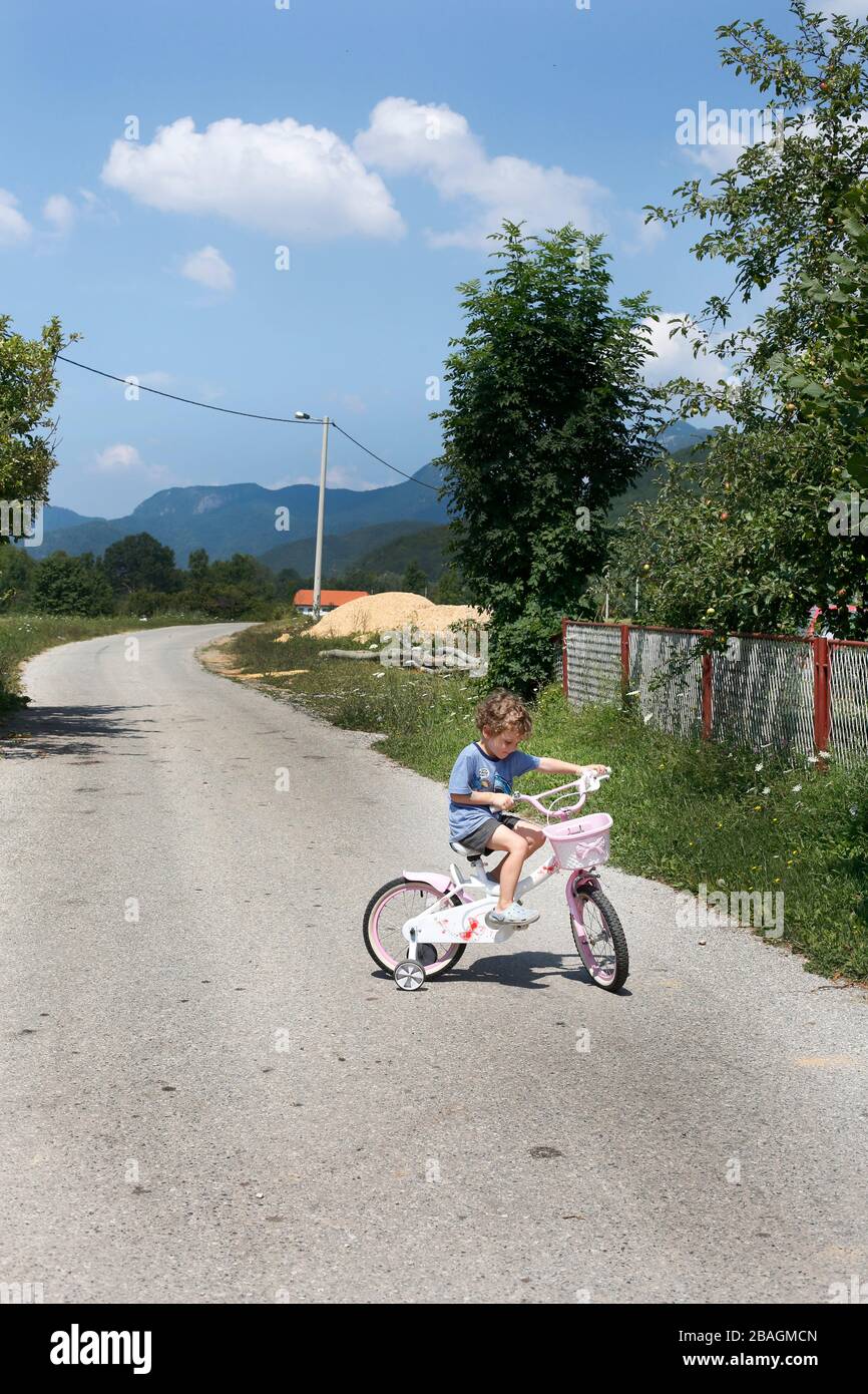 Un petit garçon à vélo sur une route vide dans les montagnes Banque D'Images