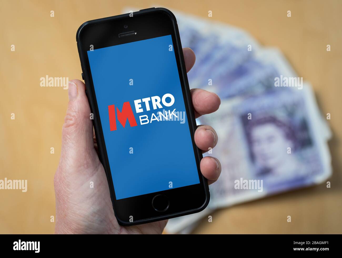 Une femme regardant le logo Metro Bank sur un téléphone mobile. (Usage éditorial uniquement) Banque D'Images