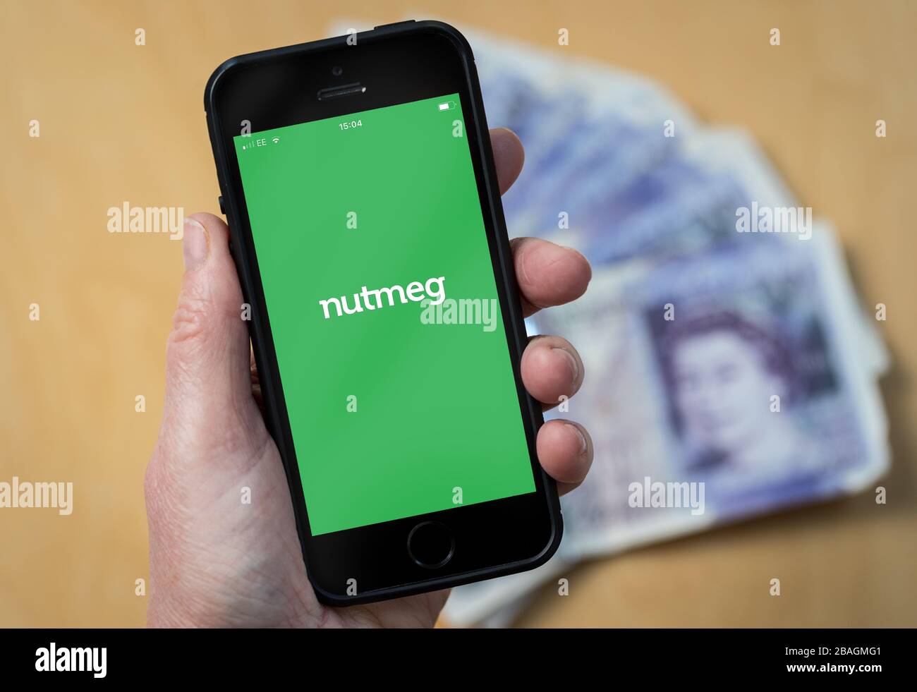 Une femme regardant le logo de la gestion d'investissement en ligne de Nutmeg sur un téléphone mobile. (Usage éditorial uniquement) Banque D'Images