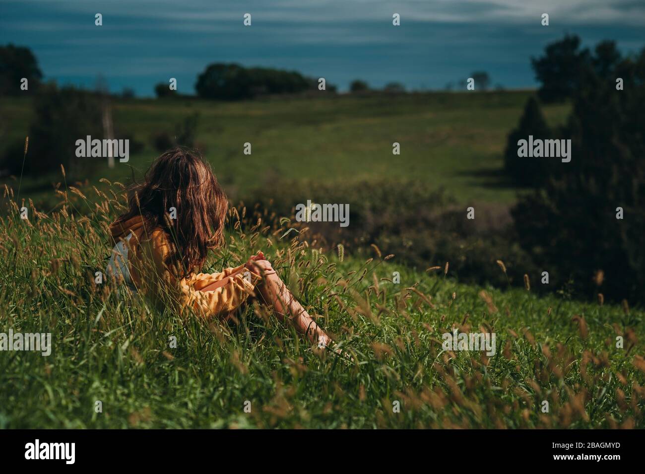 Tween fille regardant loin sur une colline verte avec des skys sombres Banque D'Images
