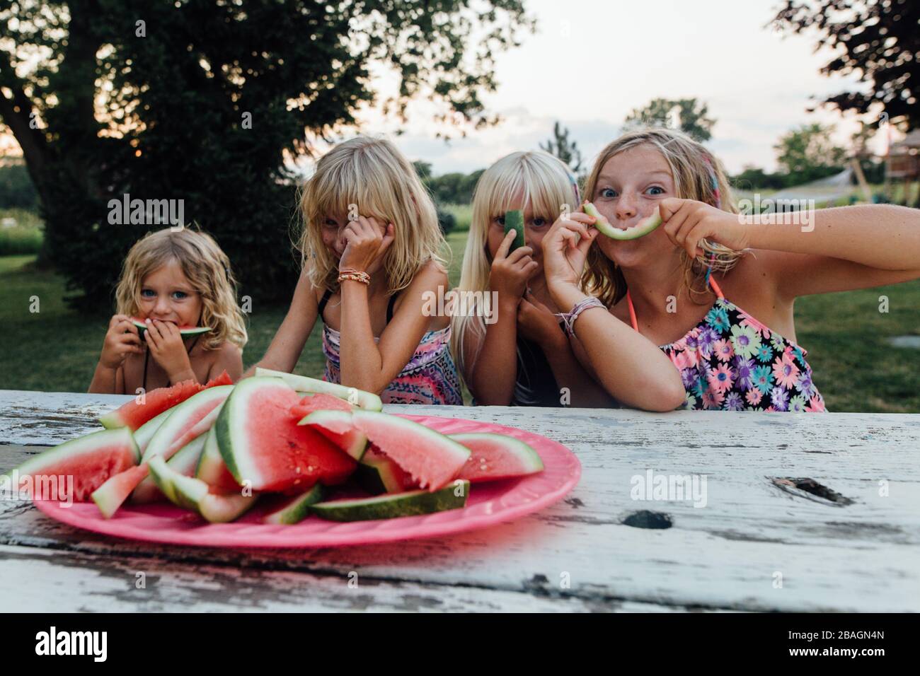 Les jeunes enfants s'amusent à manger du melon d'eau dehors en riant en été Banque D'Images