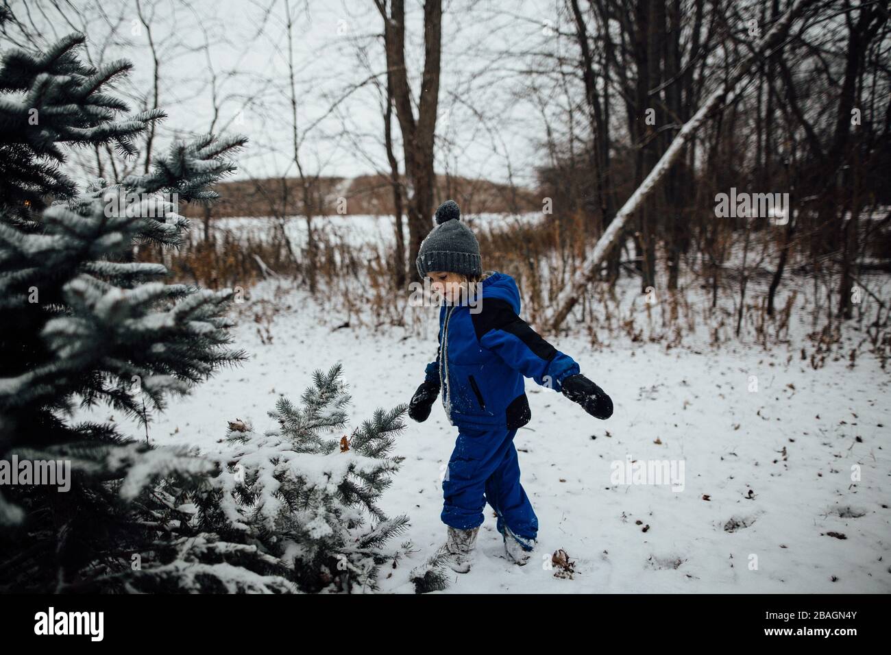 Petit garçon en combinaison de neige jouant dans la neige pendant l'hiver Banque D'Images