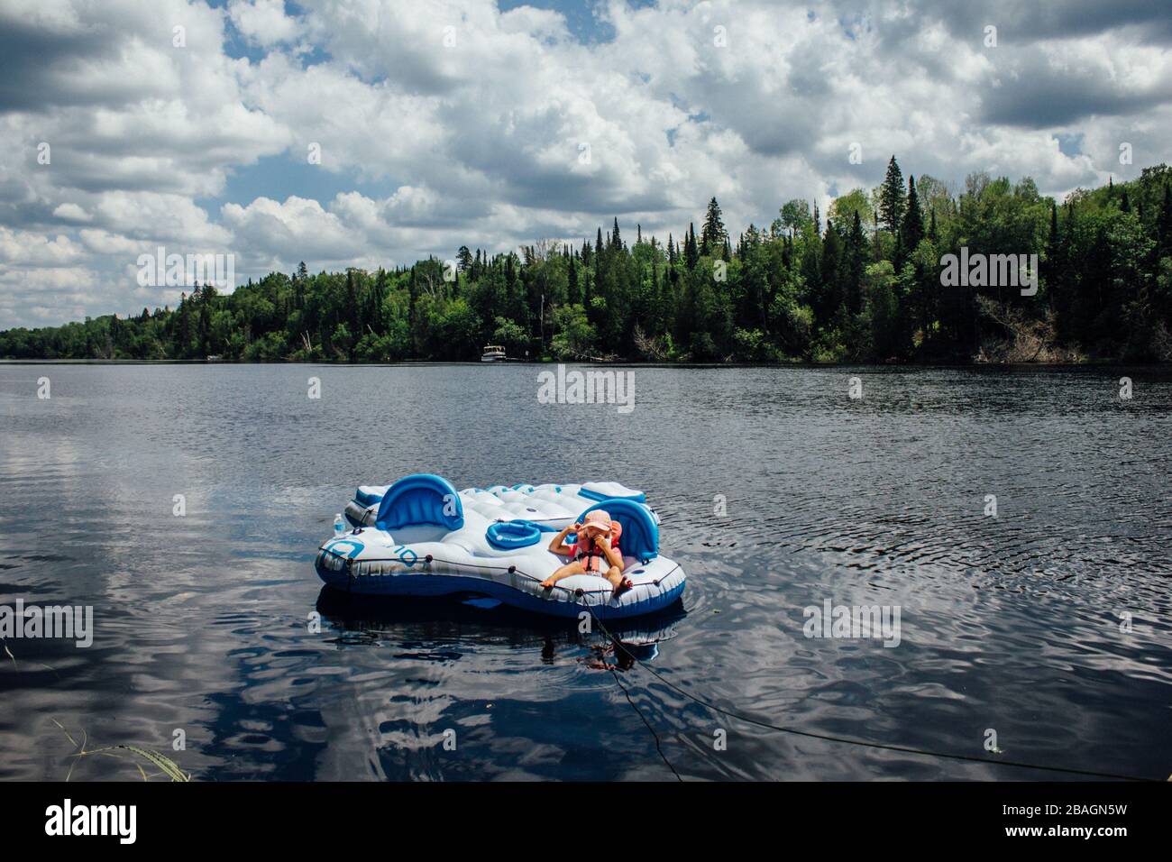 Jeune enfant ponçant sur un radeau flottant sur la rivière dans le nord de l'ontario Banque D'Images