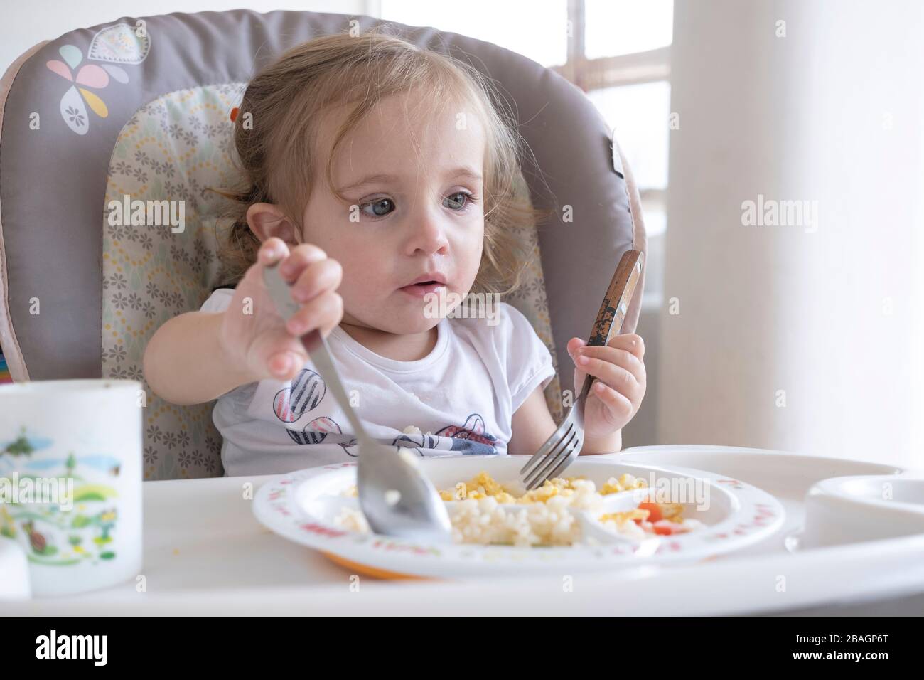 Petite fille mangeant seule dans la chaise près de la table. Banque D'Images