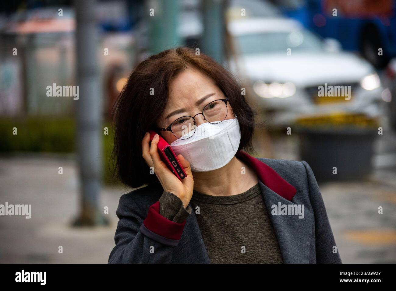 Femme portant un masque à l'aide de son téléphone portable pendant la pandémie de Coronavirus, Séoul, Corée Banque D'Images