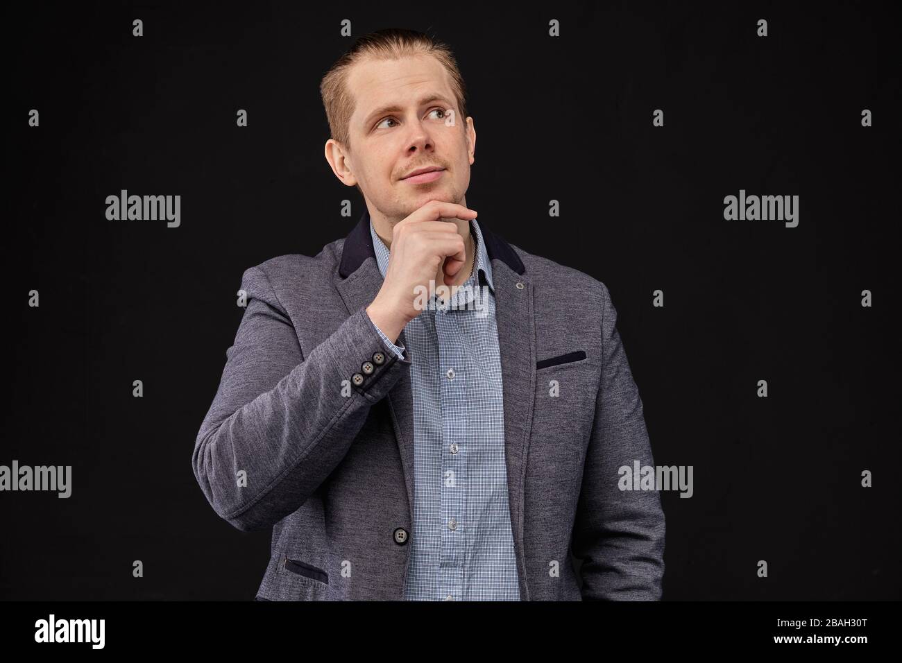 Un homme dans une veste regardant avec un look pensif sur un fond noir. Gros plan. Banque D'Images