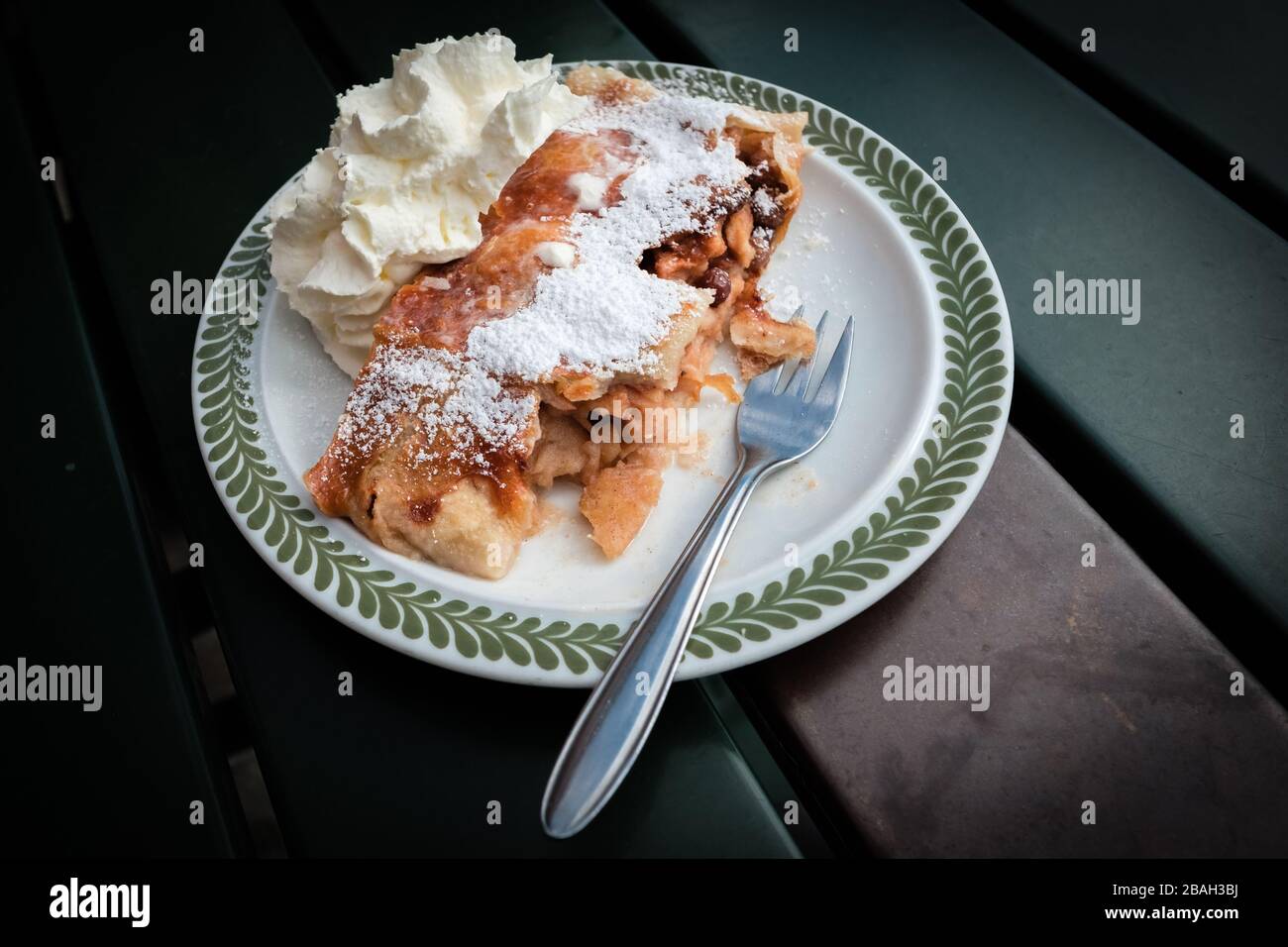 Apfelstrudel emblématique. Strudel de pomme autrichienne chargée de pommes tranchées et de raisins secs, enrobées de sucre glace et servies avec de la crème fouettée Banque D'Images