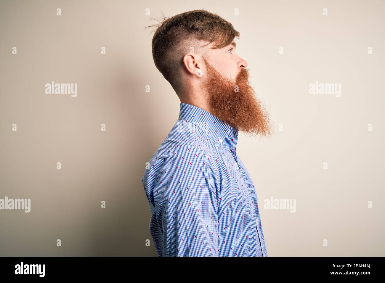 Beau homme d'affaires irlandais à tête rouge avec barbe debout sur un arrière-plan isolé regardant sur le côté, se détendre profil pose avec le visage naturel avec confiance Banque D'Images