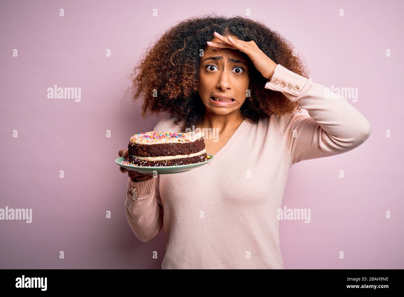 Jeune Femme Africaine Americaine Avec Des Cheveux Afro Tenant Un Delicieux Gateau D Anniversaire Souligne Avec Main Sur La Tete Choquee Avec La Honte Et Le Visage Surprise En Colere An Photo Stock