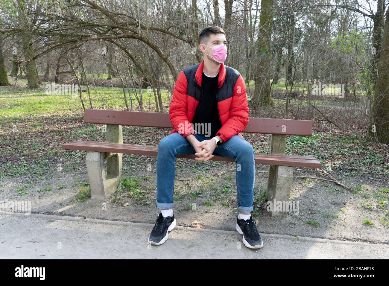 Portrait de l'homme brunette dans un bandage chirurgical assis dans le parc sur le banc, coronavirus, maladie, infection, quarantaine, masque médical Banque D'Images