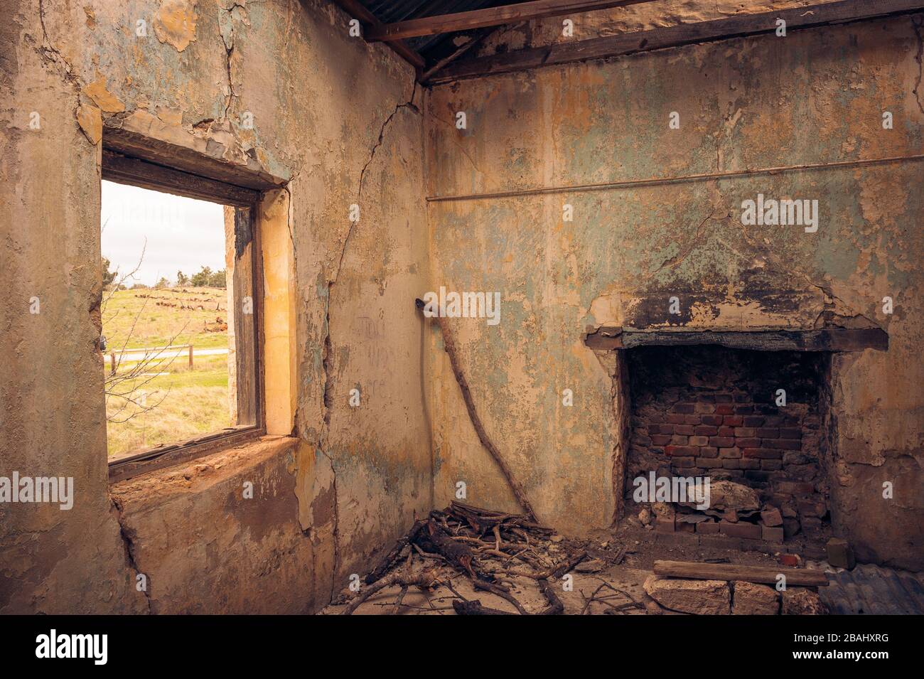 La salle de séjour d'un ancien bâtiment abandonné avec un jeune colon qui regarde la cheminée et la fenêtre ouverte donnant sur la vallée dans la chaîne des Flinders. Banque D'Images