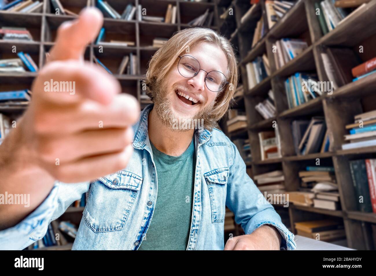Jeune barbu sourire étudiant blogger regarder point à l'appareil photo. Banque D'Images