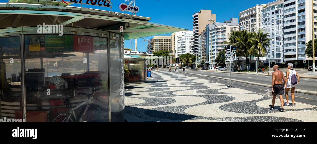 Panorama d'un kiosque fermé avec un couple âgé passant sur le boulevard Copacabana à midi pendant l'éclosion du virus COVID-19 Corona Banque D'Images