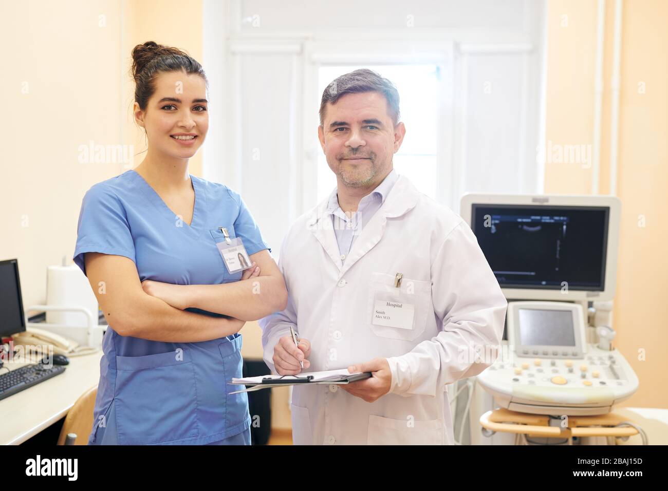 Équipe de médecins professionnels avec des badges sur des coffres debout dans la salle d'examen des ultrasons et regardant l'appareil photo Banque D'Images