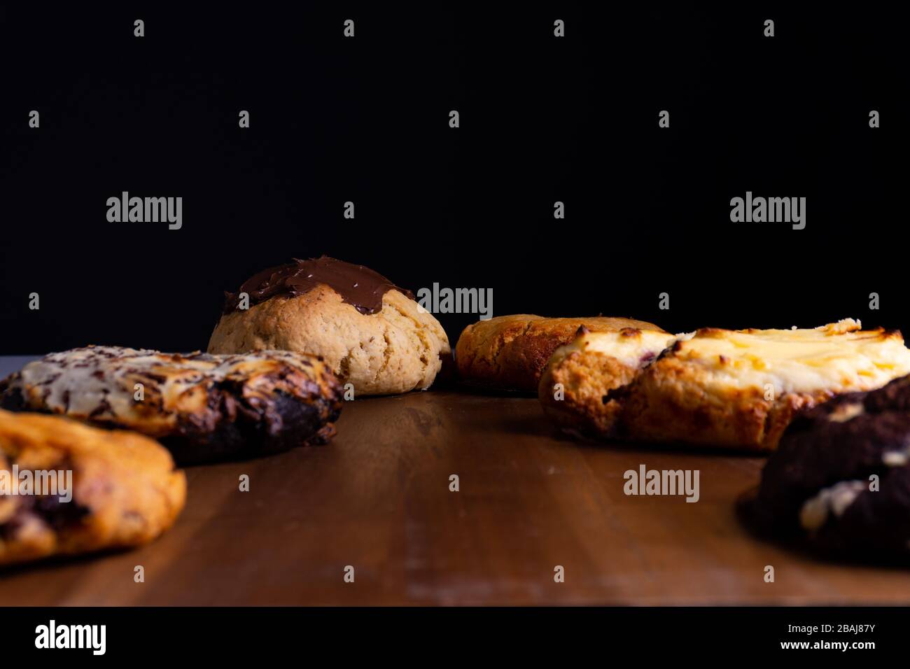 Différents gâteaux à base de cookies se posant sur une planche en bois devant un fond noir Banque D'Images