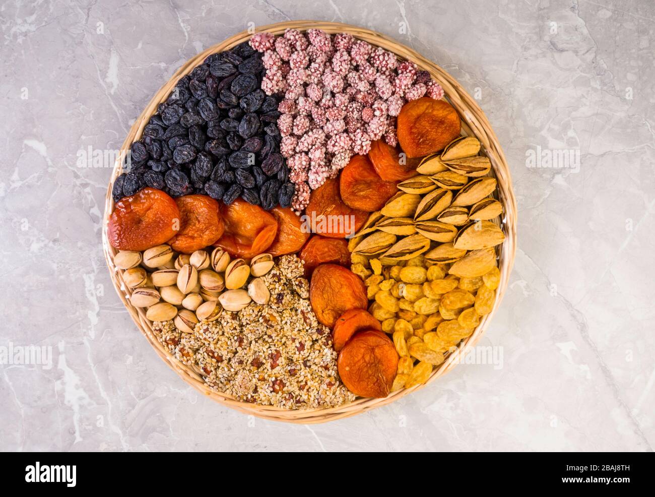 Plaque en bois avec assortiment de noix, abricots, raisins secs, sésame