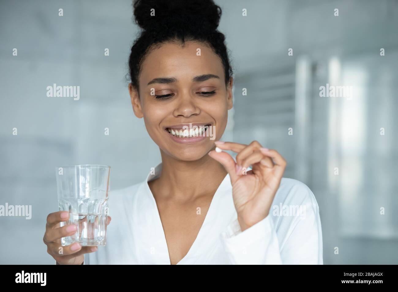 Portrait en tête femme africaine tenant la pilule et le verre d'eau Banque D'Images