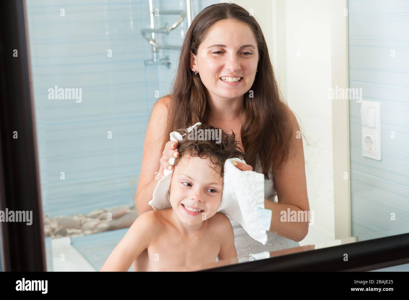 drôle de famille moment mère femme séchage de son petit garçon fils cheveux mouillés dans la salle de bains regardant dans le miroir Banque D'Images