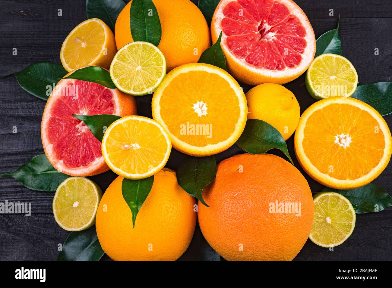 fruits, demi-pamplemousses, citrons, oranges, limes à feuilles vertes se trouvent sur une table en bois marron. arrière-plan. vue de dessus Banque D'Images