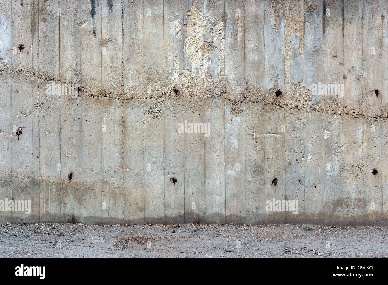 un mur extérieur en béton gris rugueux avec une partie de la surface du sol, empreintes visibles de planches en bois, deux fois remplies Banque D'Images