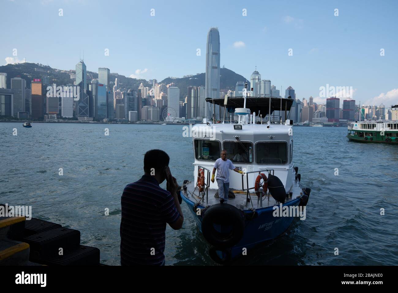 Les gens qui font une promenade le long du port de Hong Kong dans l'après-midi avec les gratte-ciel en arrière-plan Banque D'Images