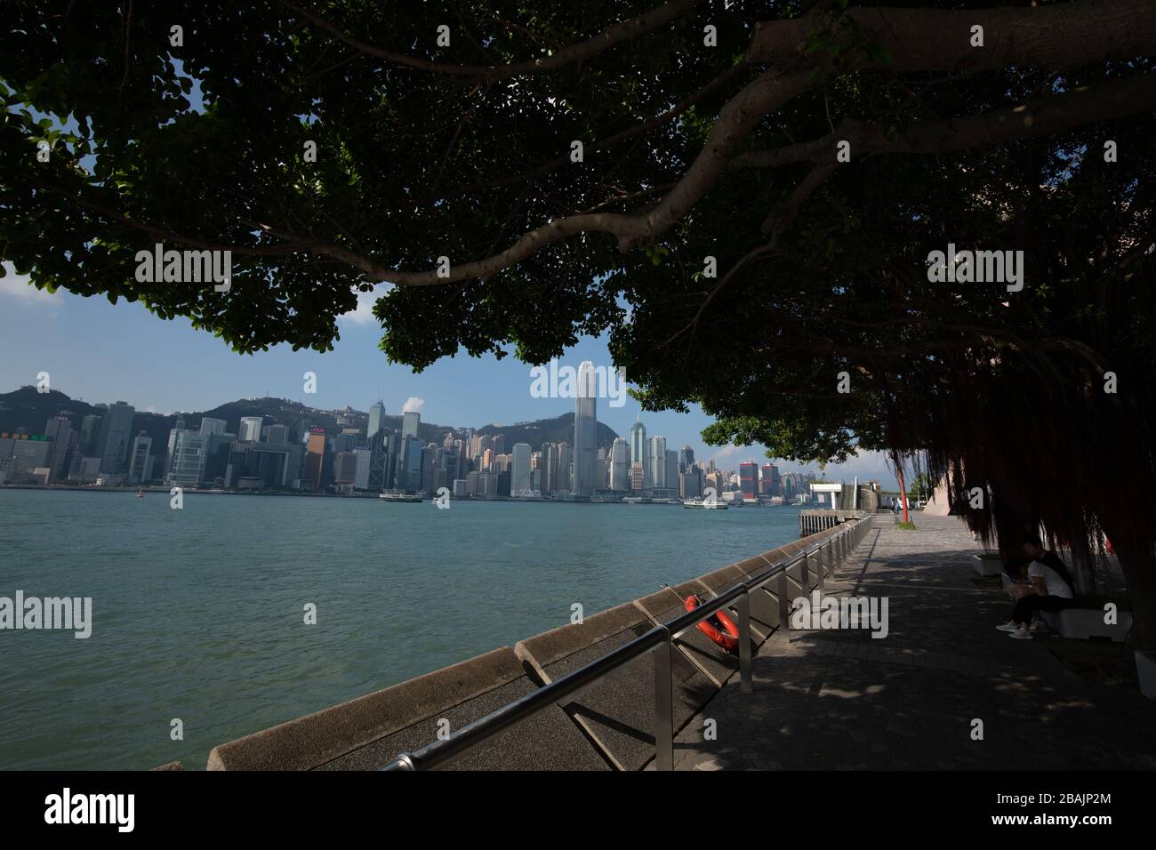 Les gens qui font une promenade le long du port de Hong Kong dans l'après-midi avec les gratte-ciel en arrière-plan Banque D'Images