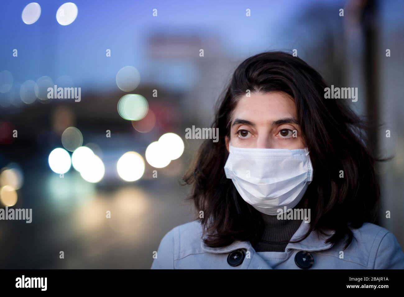 Une femme portant un masque facial et se tenant à l'extérieur pendant l'éclosion de Coronavirus Banque D'Images