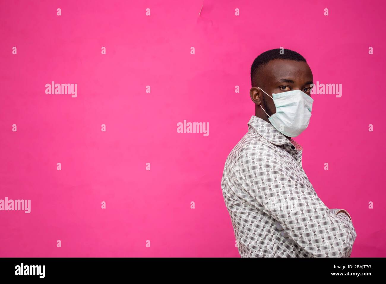 un jeune médecin africain isolé sur fond rose portant un masque facial pour se prévenir de l'éclosion, de la maladie et de la grippe. Banque D'Images