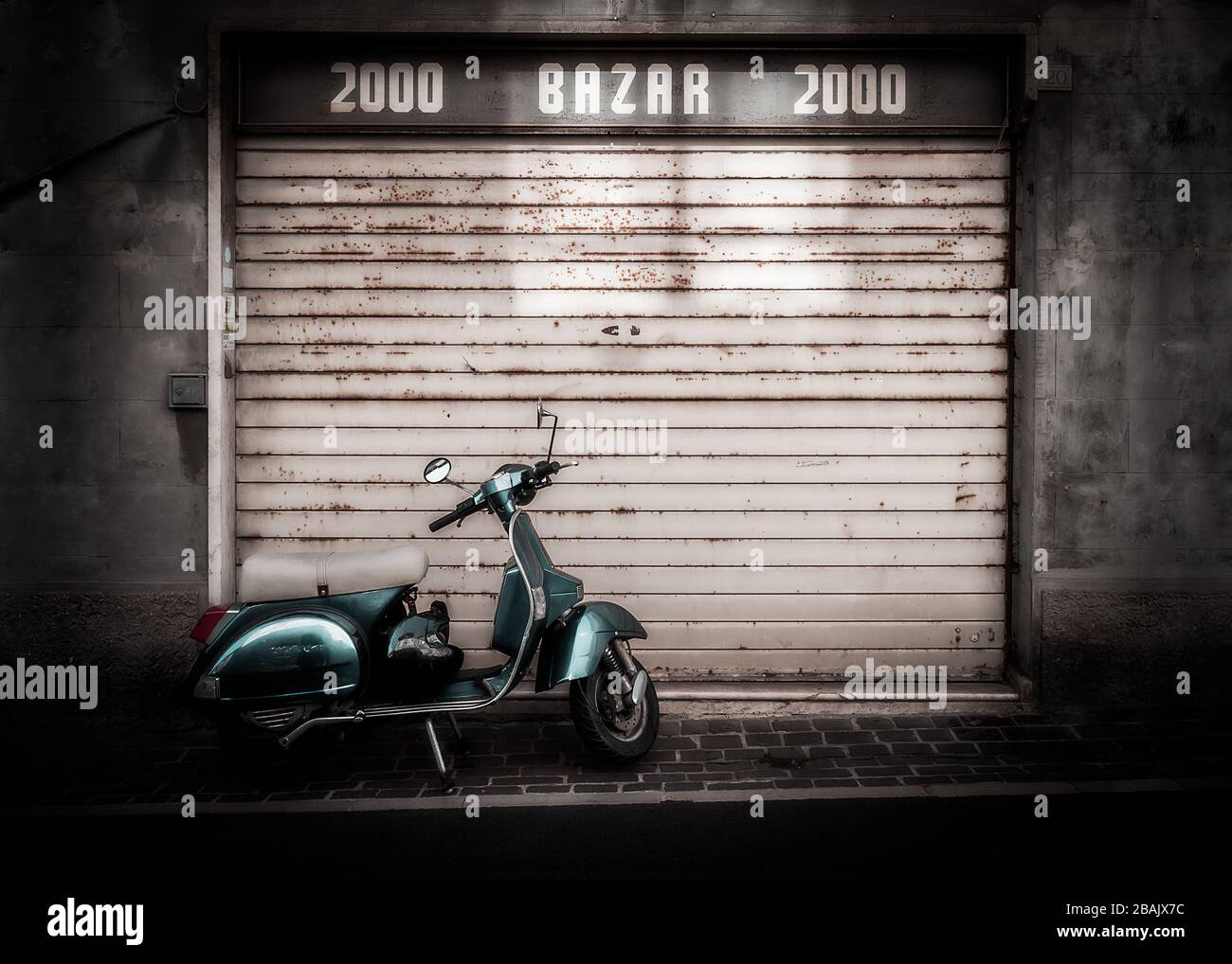 Un scooter italien classique stationné dans la rue devant un obturateur en métal rouillé d'un vieux magasin avant, Numana, Italie Banque D'Images