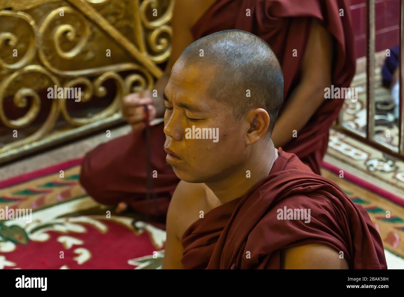 Moines bouddhistes priant dans le temple de Bouddha de Mahamaruni, Mandalay, Myanmar Banque D'Images