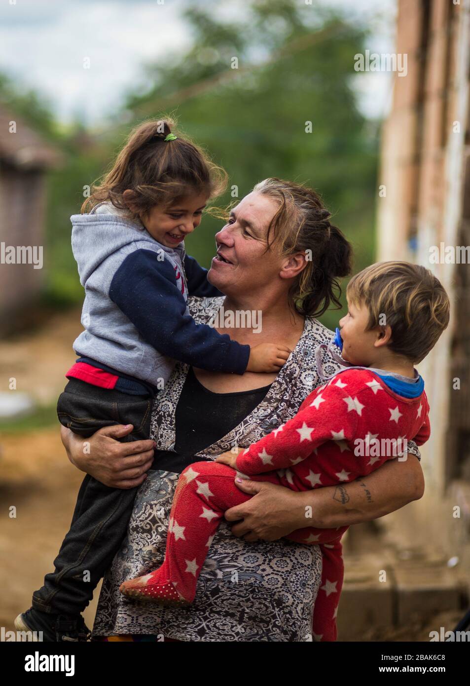 Femme avec ses petits-enfants dans une communauté rom/tzigane pauvre en Hongrie rurale Banque D'Images