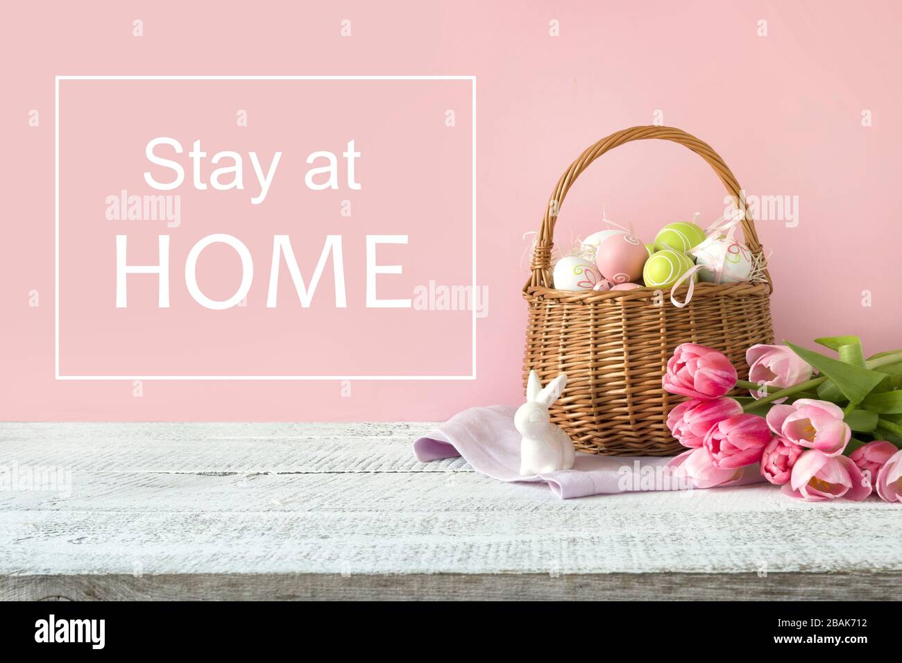 Panier en osier avec œufs de pâques et tulipes roses. Printemps fond rose de pâques. Slogan - séjour à la maison. Banque D'Images