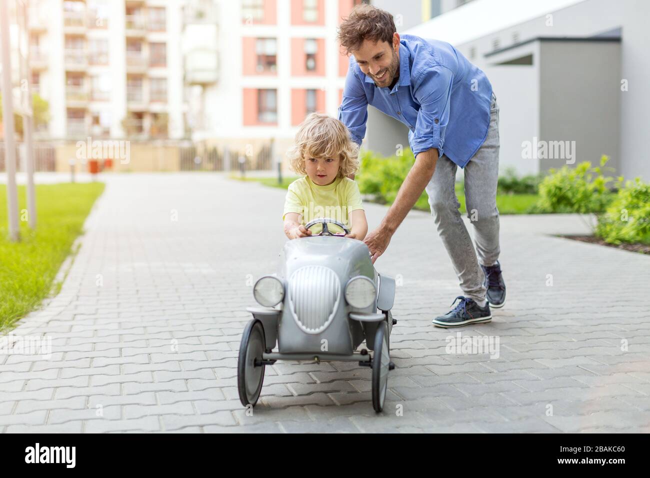 Père aidant son fils à conduire une voiture de pédalier jouet Banque D'Images