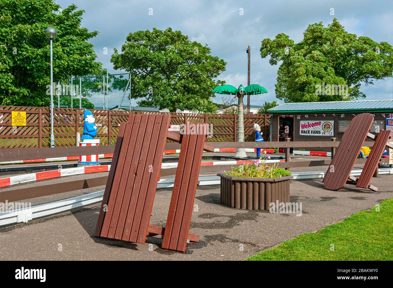 Des tables brunes et des bancs attachés se reposent sur le périmètre d'un circuit de course amusant pour les enfants en tant que policiers en plastique se dressent sur l'île centrale Banque D'Images
