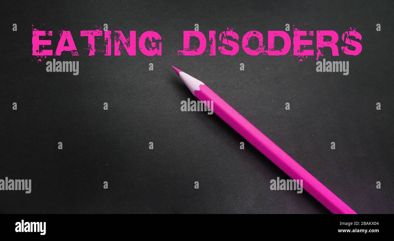 Mots de trouble de la consommation écrits avec un crayon rose sur fond sombre. Weightloss anorexia boulimia concept de santé Banque D'Images