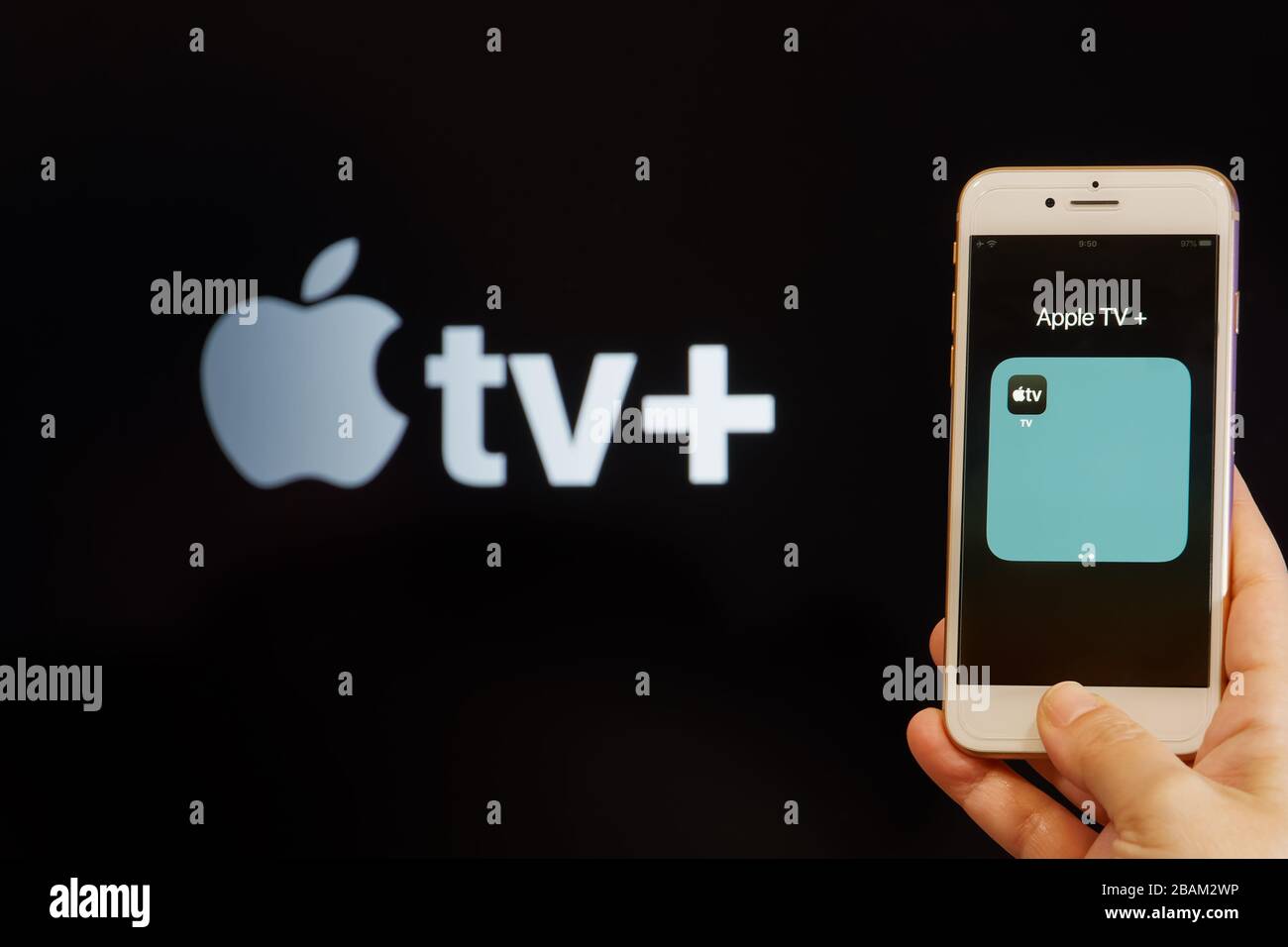 Concept de fournisseur de contenu VOD Apple Streaming Service. La main tient avant l'écran d'un iPhone mobile avec Apple TV et le logo de l'application de montre en ligne. Banque D'Images